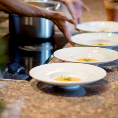 Elegant hotel dining with chef preparing gourmet starter dishes in a stylish restaurant setting. Exquisite culinary experience.