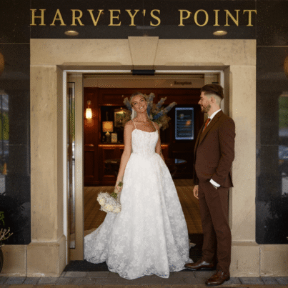 Elegant couple at hotel entrance with welcoming lights and lush green surroundings, ideal for romantic stays.