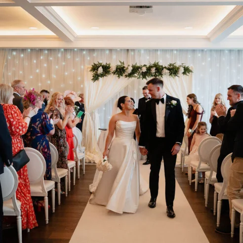 Elegant wedding ceremony with joyful couple in a stylish hotel venue, featuring modern decor and lush greenery.