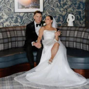 Elegant couple relax on plush tartan sofa in hotel lobby, surrounded by stylish decor and modern art.