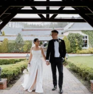 Couple holding hands under charming gazebo in lush garden, enjoying romantic, scenic hotel grounds with lantern-lit path.