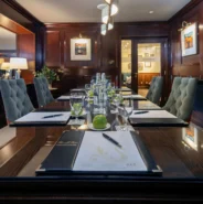 Elegant hotel conference room with plush chairs, polished wooden table, stylish décor, and complimentary refreshments.