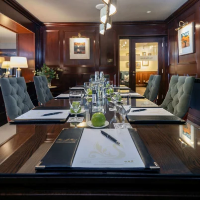 Elegant hotel conference room with plush chairs, polished wooden table, stylish décor, and complimentary refreshments.